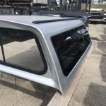 Camper shell with tinted windows and sleek silver finish, perfect for trucks and outdoor adventures.