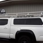 Aluminum roof rack installed on a white pickup truck for sport gear transportation.