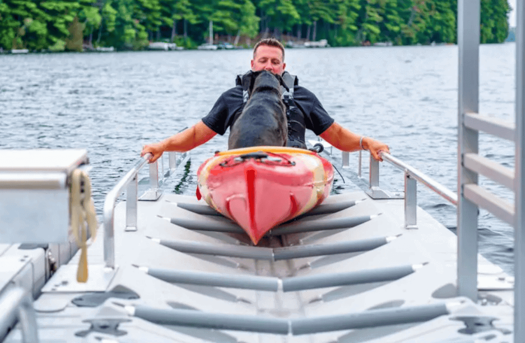 Man with kayak on lake at Camp & Cruise boat rental facility.