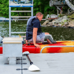 Man preparing kayak for lake, outdoor fishing and water sports activity.