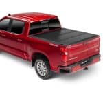 Red Chevrolet pickup truck with a black bed cover at Camp & Cruise.