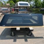 Black truck bed canopy for GMC 1500 with window, outdoor setting.