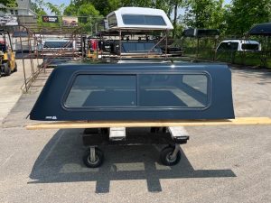 Black truck bed canopy for GMC 1500 with window, outdoor setting.