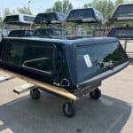 Black truck bed cap for GMC 1500 with tinted windows and aerodynamic design.