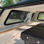 Truck cap window with tinted glass and black frame for GMC 1500.