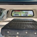 View of truck bed with black cover and rear window of GMC 1500.