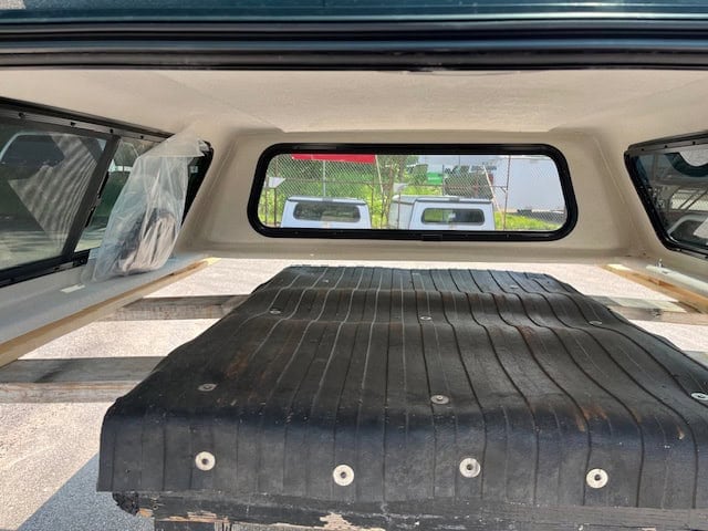 View of truck bed with black cover and rear window of GMC 1500.