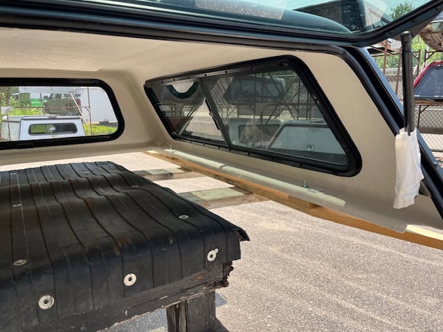 Close-up of truck cap interior with windows and storage area.