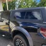 Black truck bed cover with tinted windows on a pickup truck.