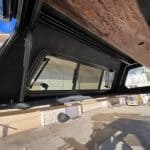 Tundra truck cap window with tinted glass and black frame.