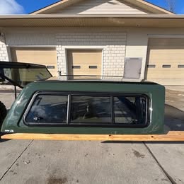 Green truck cap for Tundra with tinted windows and durable design.