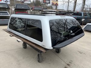Silver truck cap for Nissan Titan with tinted windows and roof rack.