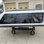 Silver truck cap with tinted windows for Nissan Titan pickup truck.