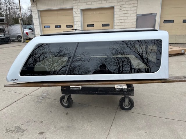 Silver truck cap with tinted windows for Nissan Titan pickup truck.