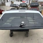 Nissan Titan truck bed cap with tinted rear window and mounting hardware.