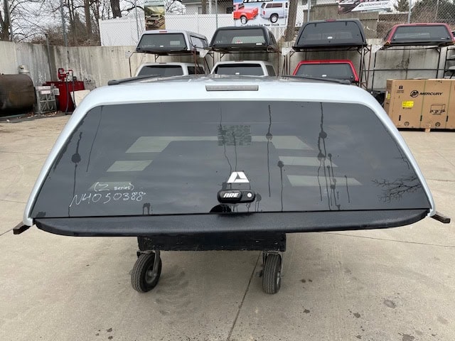 Nissan Titan truck bed cap with tinted rear window and mounting hardware.