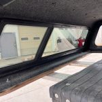 Truck bed window with tinted glass and black frame for Nissan Titan.