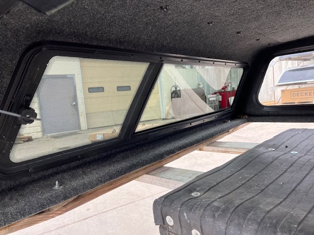Truck bed window with tinted glass and black frame for Nissan Titan.