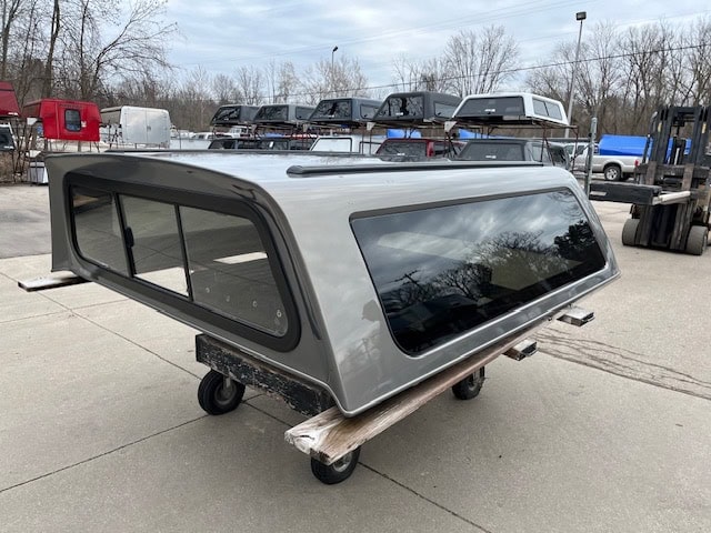 Gray truck cap with tinted windows for GMC 1500, 70-inch size, in outdoor lot.