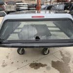 Gray 8-foot Chevy 1500 truck cap with rear window and wheels.
