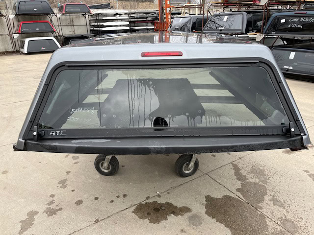 Gray 8-foot Chevy 1500 truck cap with rear window and wheels.