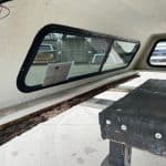 Interior view of Chevy 1500 truck cap with window and wooden bench.
