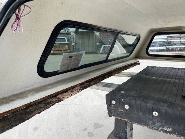 Interior view of Chevy 1500 truck cap with window and wooden bench.