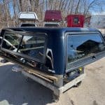 Black truck cap for Chevy 1500 with tinted windows and aerodynamic design.