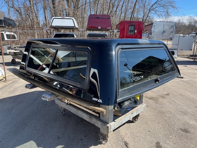 Black truck cap for Chevy 1500 with tinted windows and aerodynamic design.