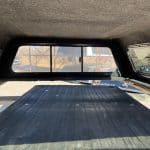 Truck bed cover with tinted rear window and black surface for RAM 1500.