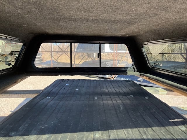 Truck bed cover with tinted rear window and black surface for RAM 1500.