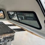 Interior view of a Chevy HD camper shell with window and storage area.