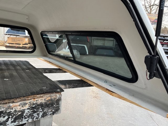 Interior view of a Chevy HD camper shell with window and storage area.