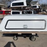 White truck cap for RAM 1500 with a lockable side window.