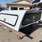 White truck camper shell with tinted windows and black trim for RAM 1500.