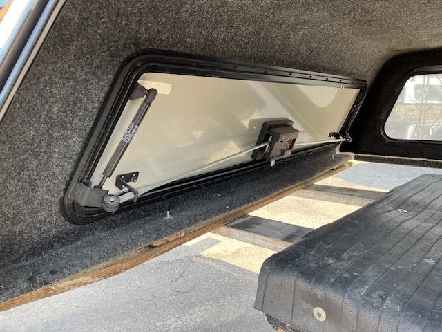 Truck bed window with hydraulic opening mechanism for easy access.