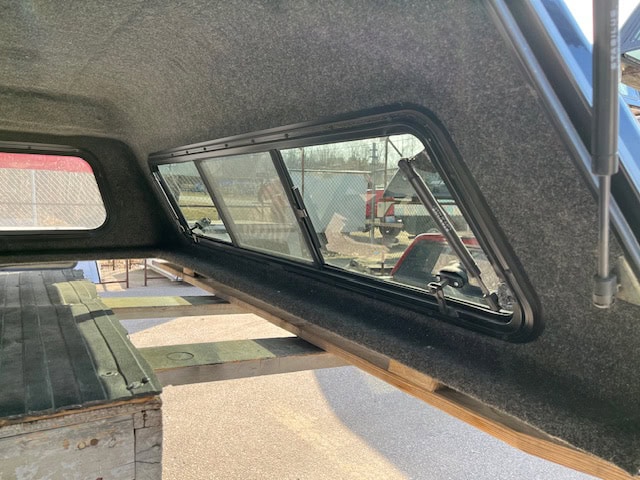 Truck cap window with tinted glass and black frame for Chevy 1500.