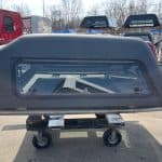 Gray truck cap for GMC 1500 with window and roof rack.