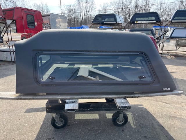 Gray truck cap for GMC 1500 with window and roof rack.