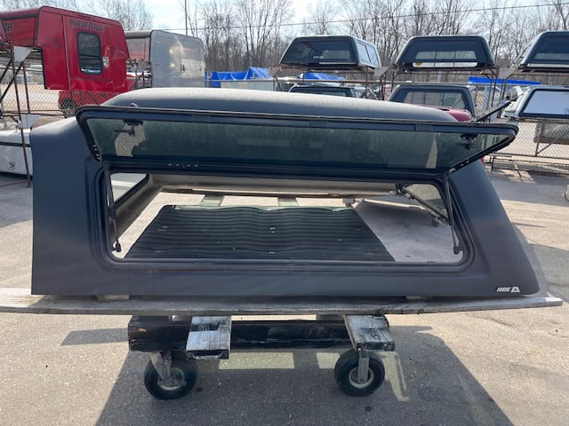 Gray truck cap for GMC 1500 with tinted window and lockable side access.