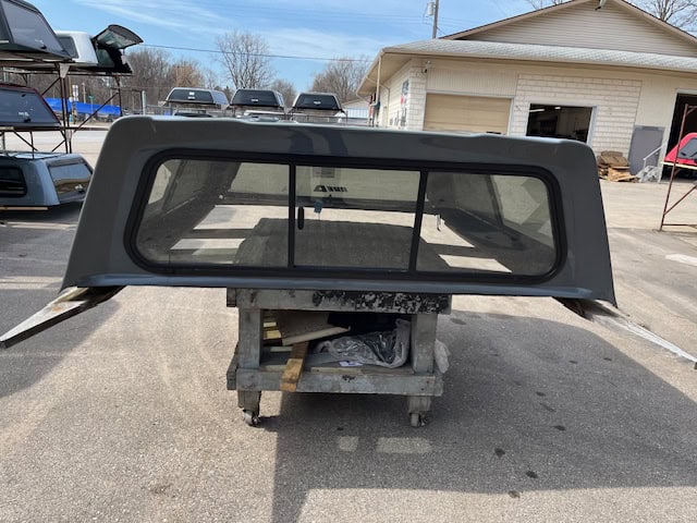 Gray truck bed cap with tinted rear window for RAM 1500.