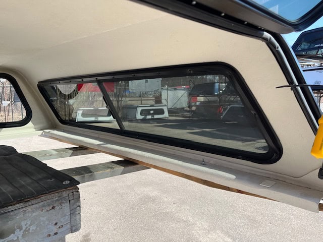 F150 truck bed window with tinted glass and black frame.