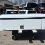 White truck bed toolbox with black trim on a flatbed truck.
