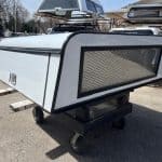 White truck camper shell with tinted window and black trim on a trailer.