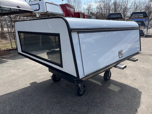 White truck camper shell with large rear window and side access door.