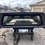 Ford F150 truck cap in gray with rear window and mounting hardware.
