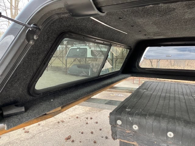 Truck bed cover with tinted windows and wooden support.