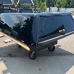 Black truck cap with tinted windows and wheelbase support.