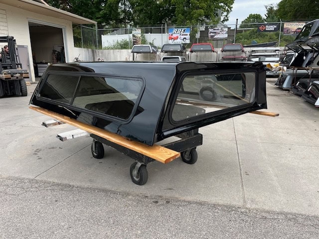 Black truck bed cap for Chevy HD 98" with tinted windows and wooden side panels.