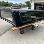 Black Chevy HD 98" truck cap with tinted windows and wooden side rail.